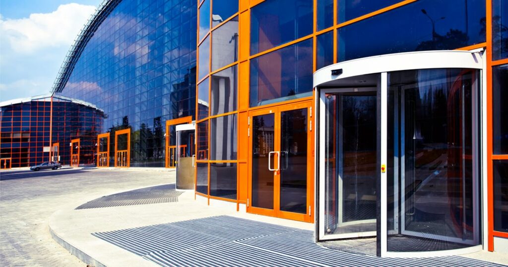 Image depicts the exterior of a building with orange commercial doors.