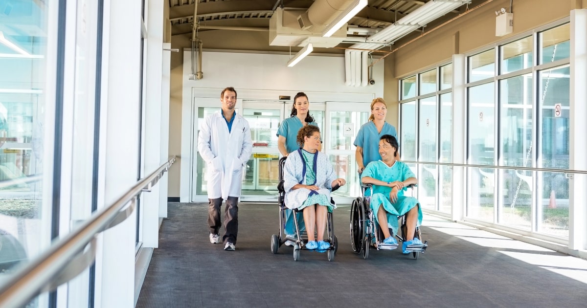 Medical staff pushing people in wheelchairs, highlighting the need for automatic door systems.