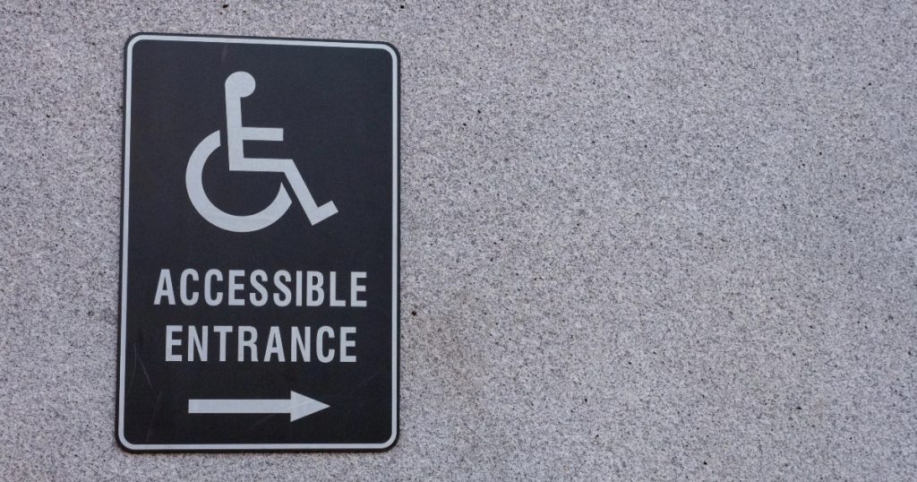 A black and white sign stating Accessible Entrance and sign for wheelchair users.
