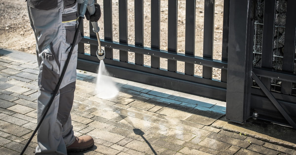 Maintenance worker removing dirt from an automatic gate track.